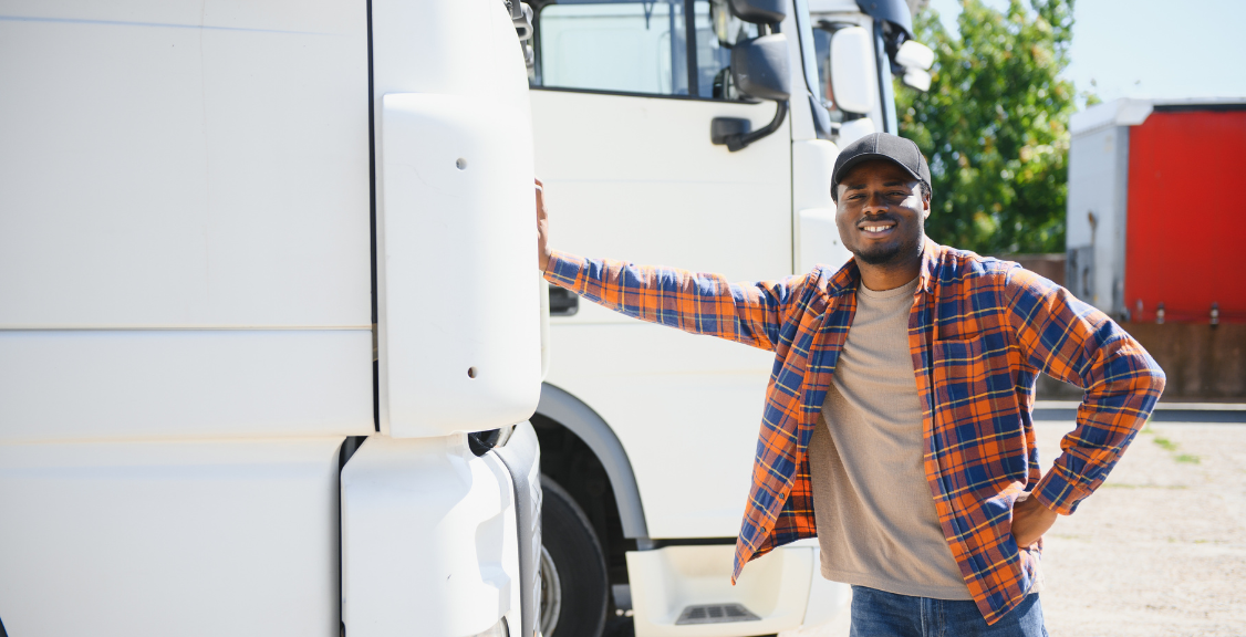 a driver smiling while leaning on the truck