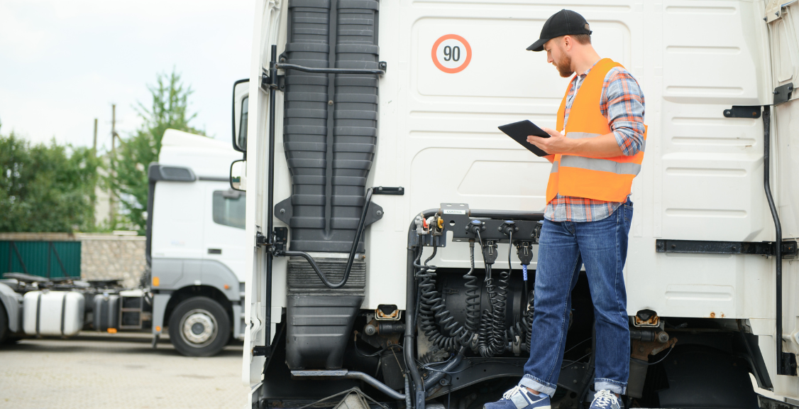A truck driver inspects the vehicle, using a tablet to record for potential unwanted GPS trackers as a privacy and security precaution