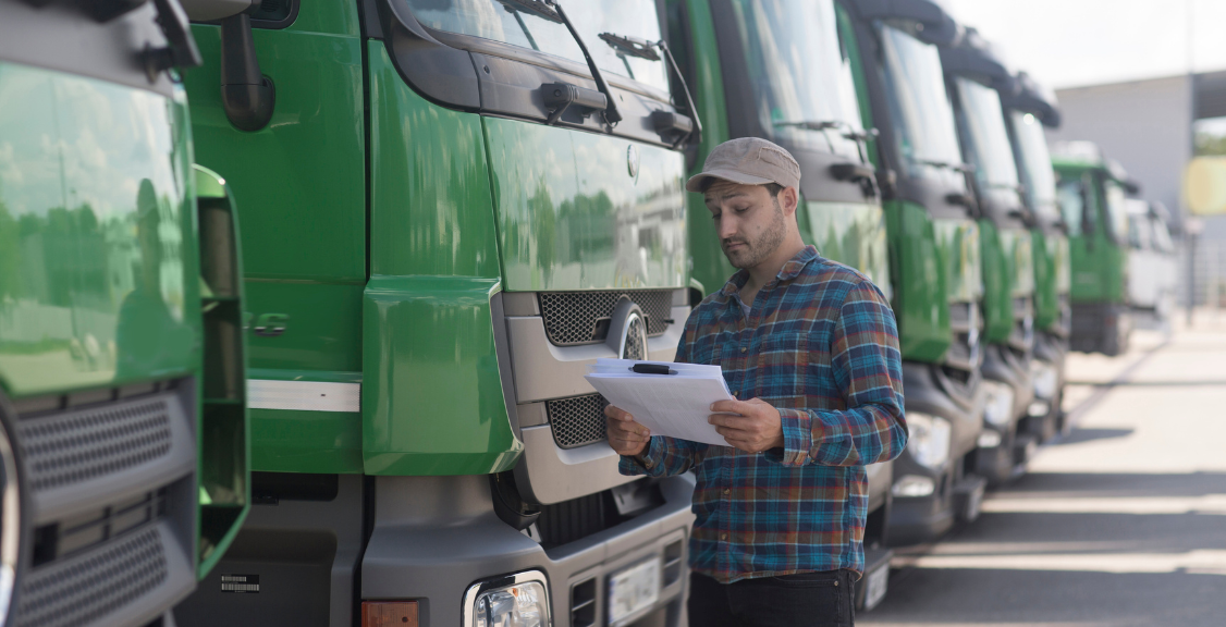Man by fleet of trucks looking at paperwork