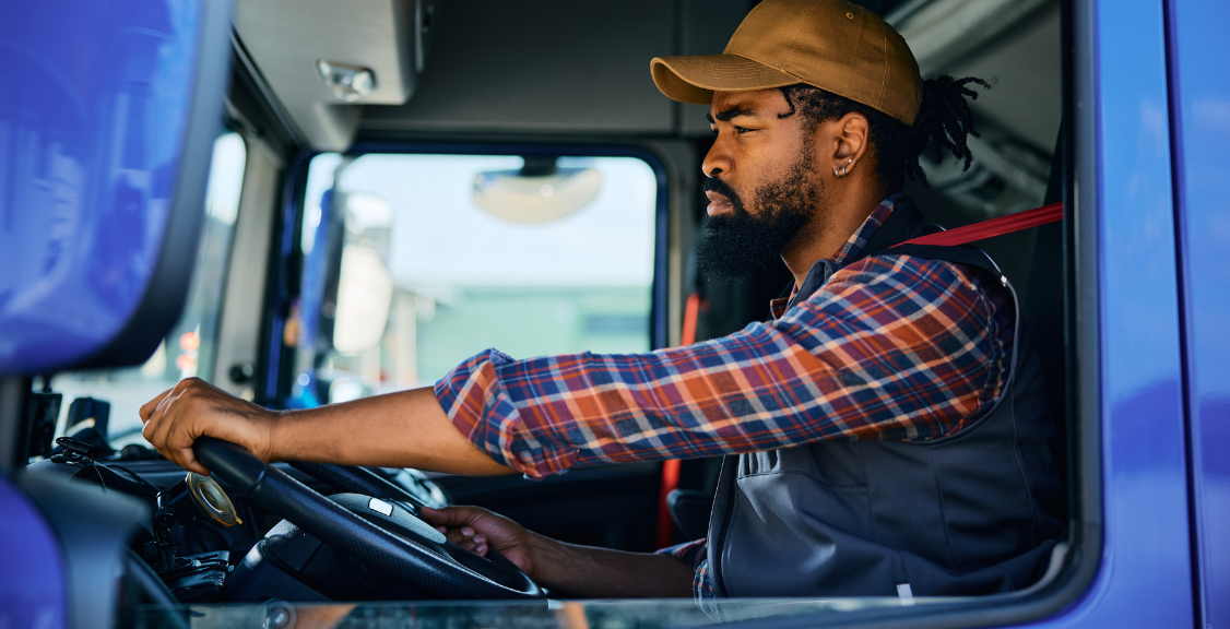 Black driver behind steering wheel of a truck