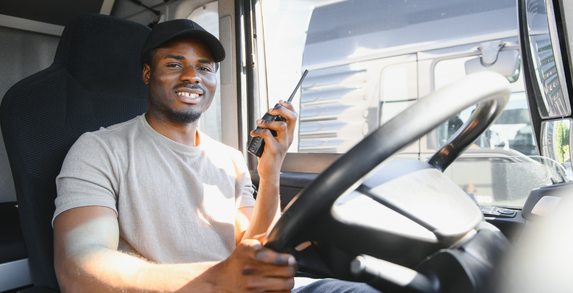 Driver smiling while using walkie talkie in cab of modern truck