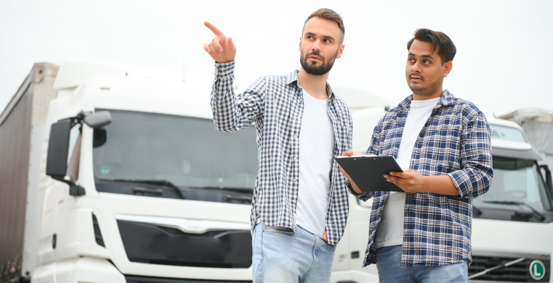 a fleet manager talking to a driver and pointing on trucks