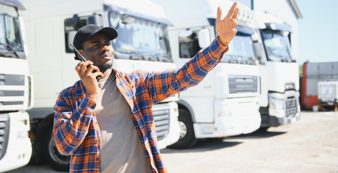 a fleet manager talking to a driver on walkie talkie and leading the truck inside the premises