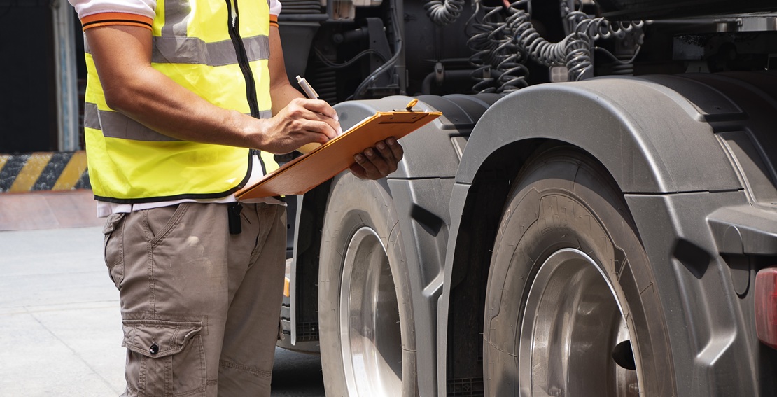 truck driver hand holding clipboard with inspecting truck wheels fleet management